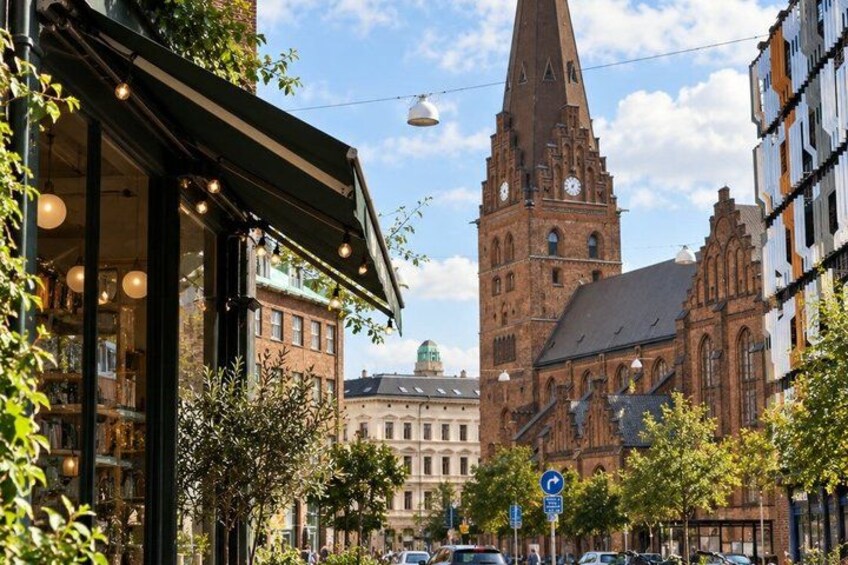 A street with a church tower, a café, and a building with a clock. 2