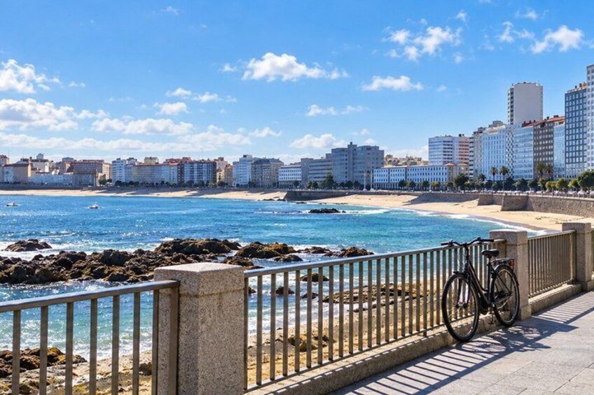 A coastal cityscape with a beach, a bicycle, and a clear blue sky. 1