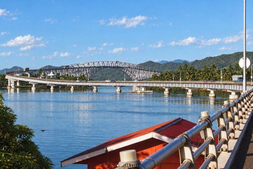 A bridge over a body of water with mountains in the background. 1