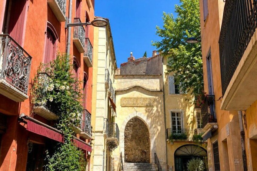 A narrow street with buildings, a wrought iron gate, and a clear blue sky. 4