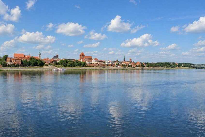 A calm river with a town on the opposite bank, featuring historic buildings and a bridge. 4