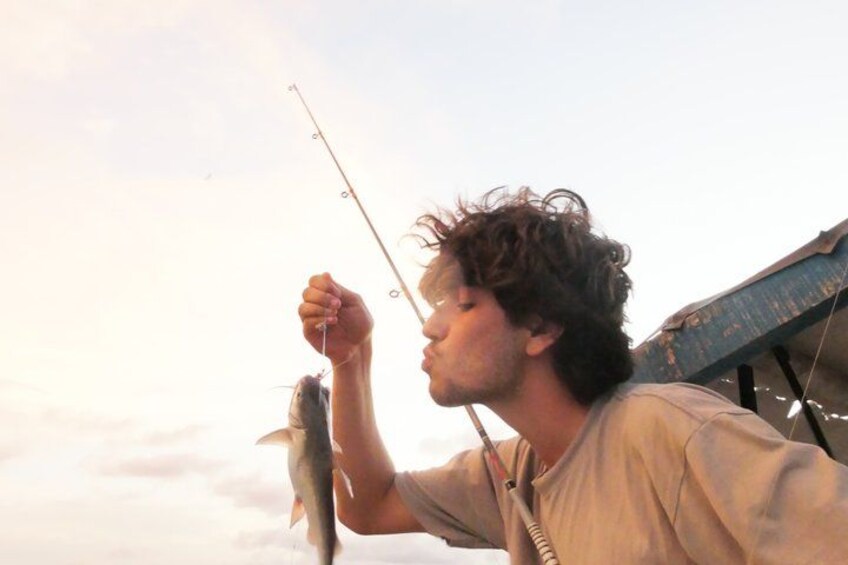 A person holding a fish with a fishing rod. 1