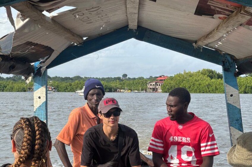 A group of people on a boat with a water body and greenery in the background. 3