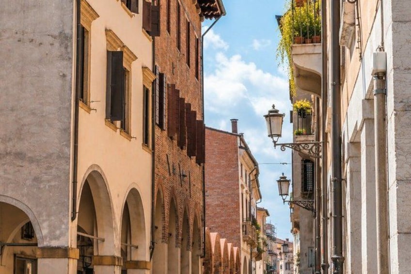 A narrow street lined with historic buildings, featuring arched doorways and traditional shutters. 4