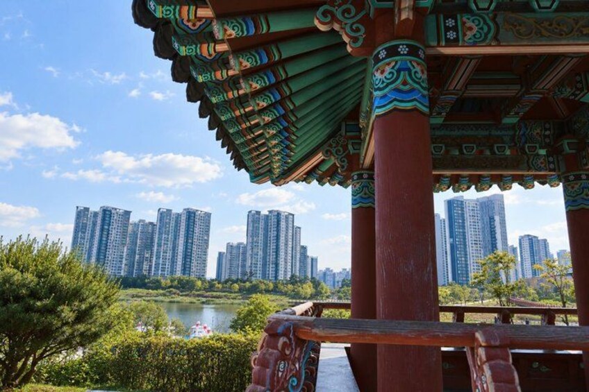 A traditional pavilion with ornate roof and columns, a river, and high-rise buildings in the background. 3