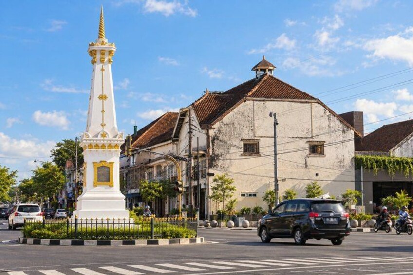 A white monument with a golden spire, a building with a tiled roof, and a street with cars and a cyclist. 4