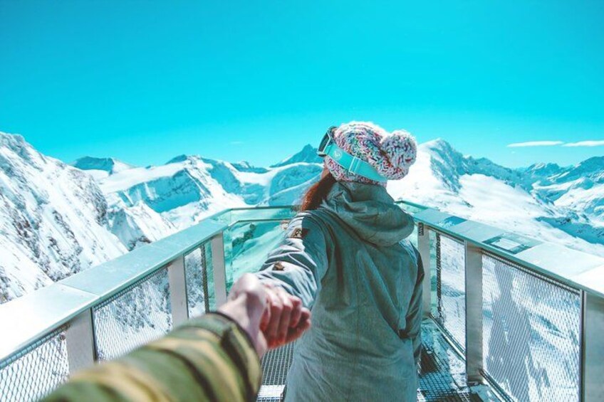 A person in a snowy mountainous landscape, holding onto a railing. 3