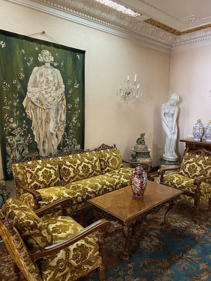 A room with ornate furniture, a large painting, a statue, and decorative vases. 3