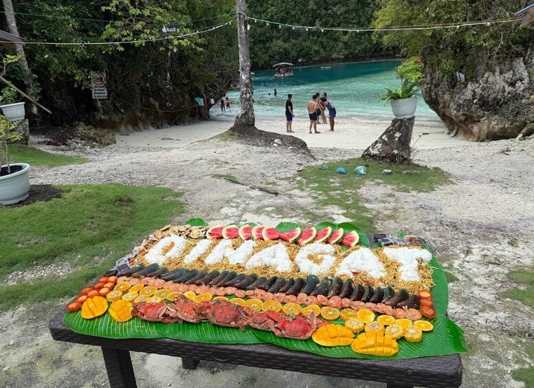A beach with a food display table featuring seafood and fruits. 2