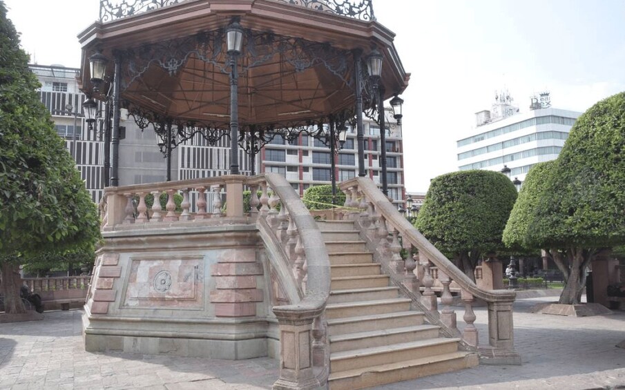 Un mirador con ornamentación metálica elaborada y una escalera de piedra. 3