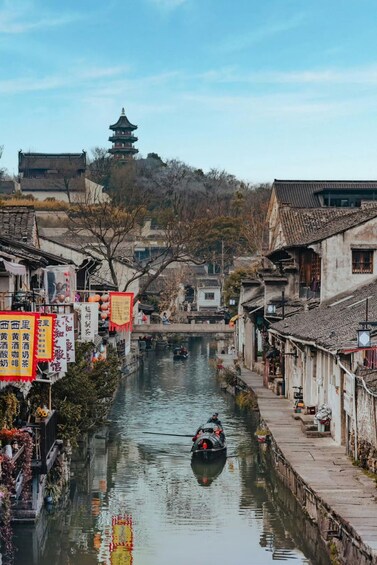 A traditional Chinese river scene with a boat, buildings, and a pagoda in the background. 2