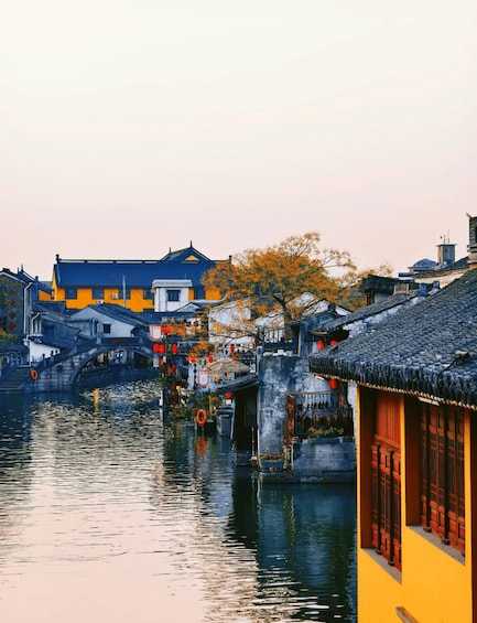 A traditional Chinese water town with wooden houses and a stone bridge over a calm river. 3