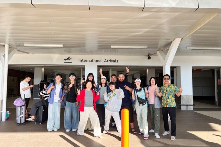 A group of people at an airport terminal with a sign reading 'International Arrivals'. 5