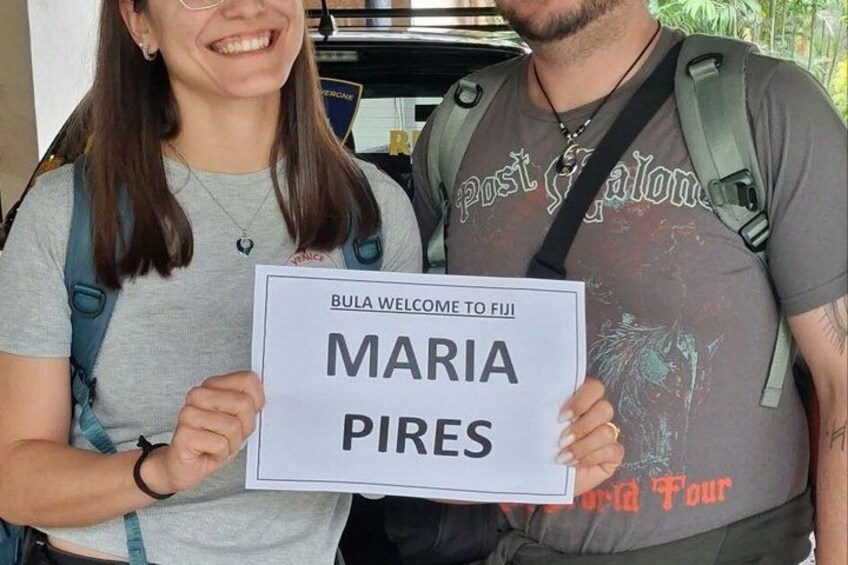 Two people holding a welcome sign for Maria Pires. 1