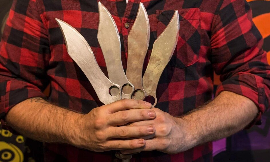 En person som håller i ett stort, metalliskt föremål med flera blad. 1