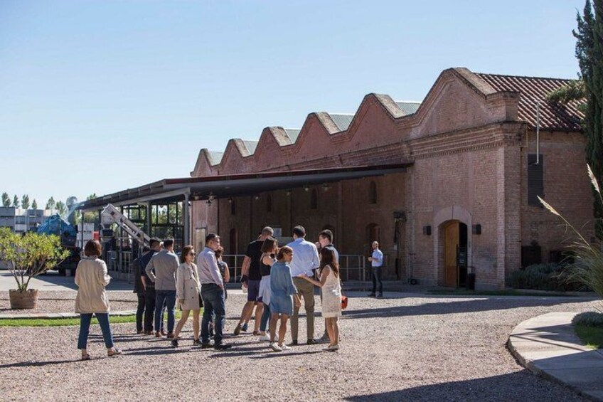 A group of people standing in front of a brick building with a covered walkway. 5