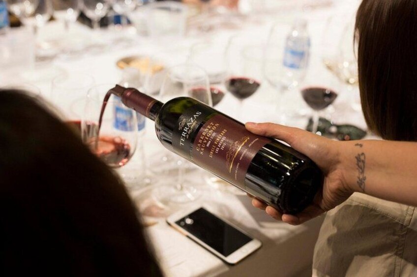 A person holding a bottle of wine, pouring it into a glass. 3