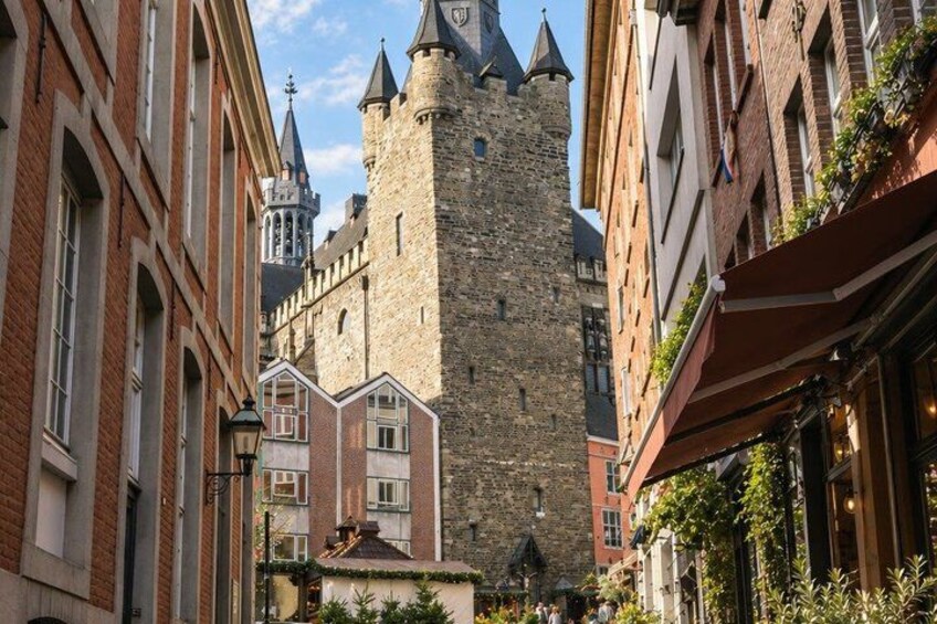 A historic stone tower, red brick buildings, and a narrow street with greenery. 5