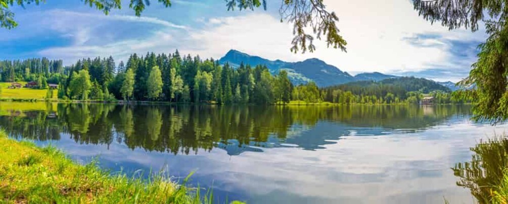 A calm lake surrounded by trees and mountains. 5