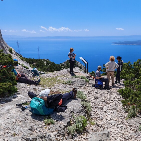 A group of hikers on a rocky mountain trail with a view of the sea. 2