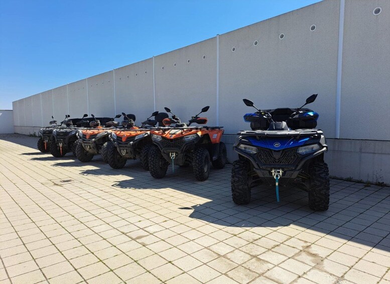A row of ATVs parked against a wall. 1