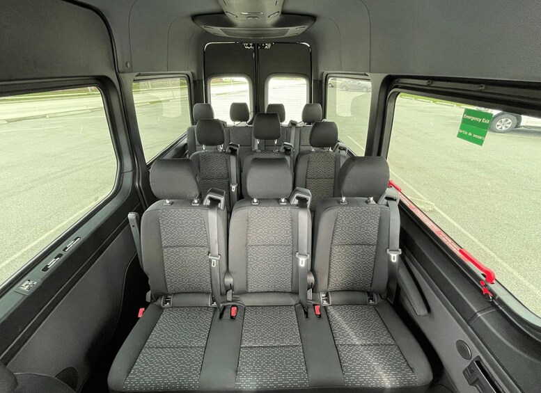 The interior of a vehicle with multiple rows of seats and a rear view of a parking lot. 4
