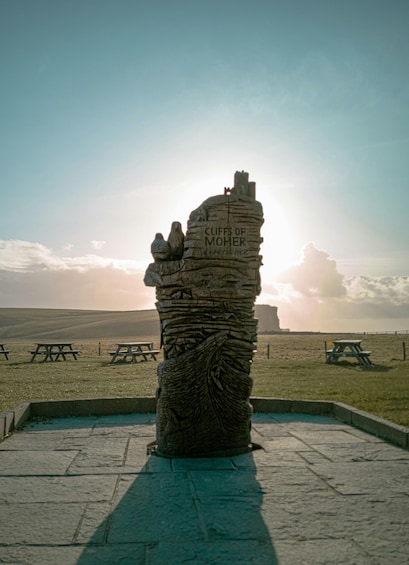 Ein Steins Denkmal mit Inschriften, umgeben von Picknicktischen und einem klaren Himmel. 2