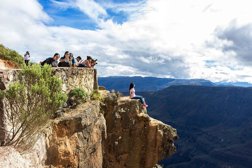 A group of people on a rocky cliff overlooking a vast canyon. 4