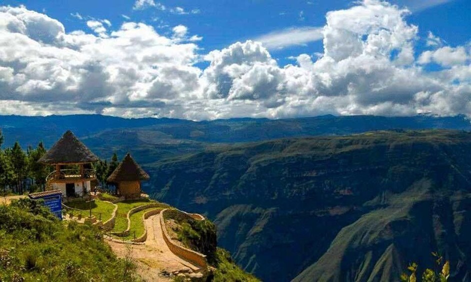 A mountainous landscape with a thatched-roof hut and a paved path. 3