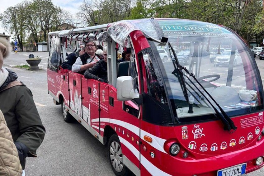 A red and white tour bus with 'Vietto Gran Tour' written on the side, parked on a street with people around. 5