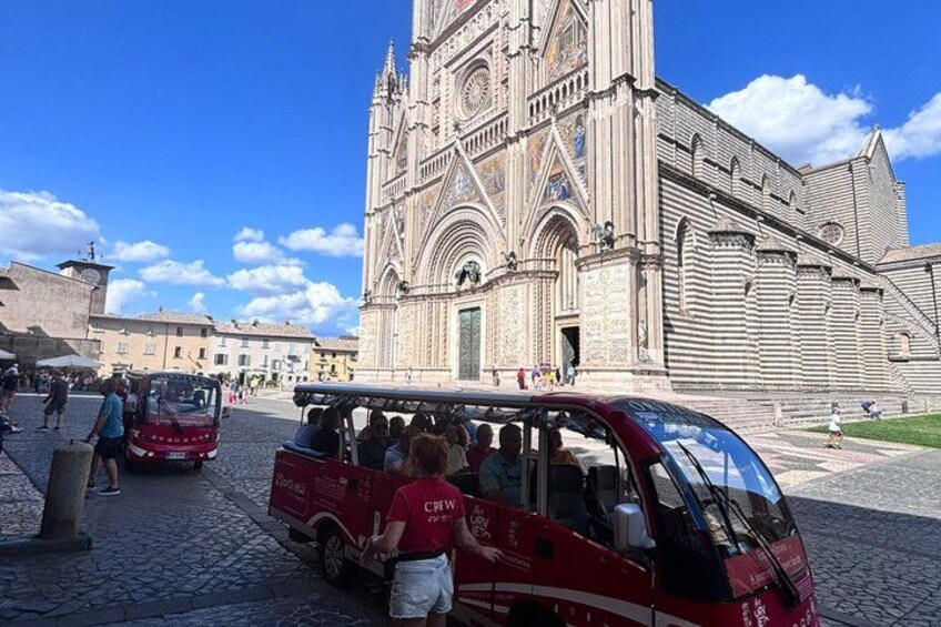 A historic cathedral with intricate architecture, a red tour bus, and cobblestone streets. 1