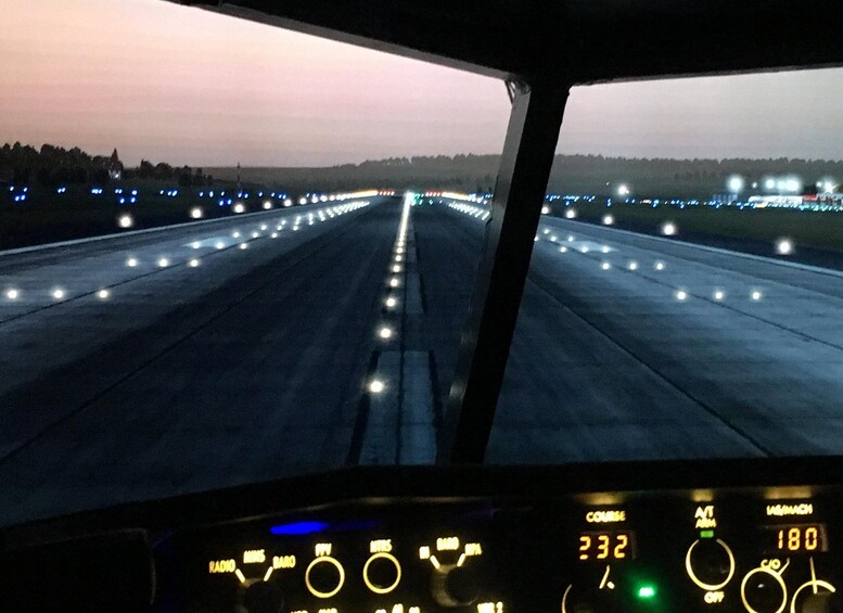 A vehicle's dashboard with illuminated gauges and a runway view at dusk. 5