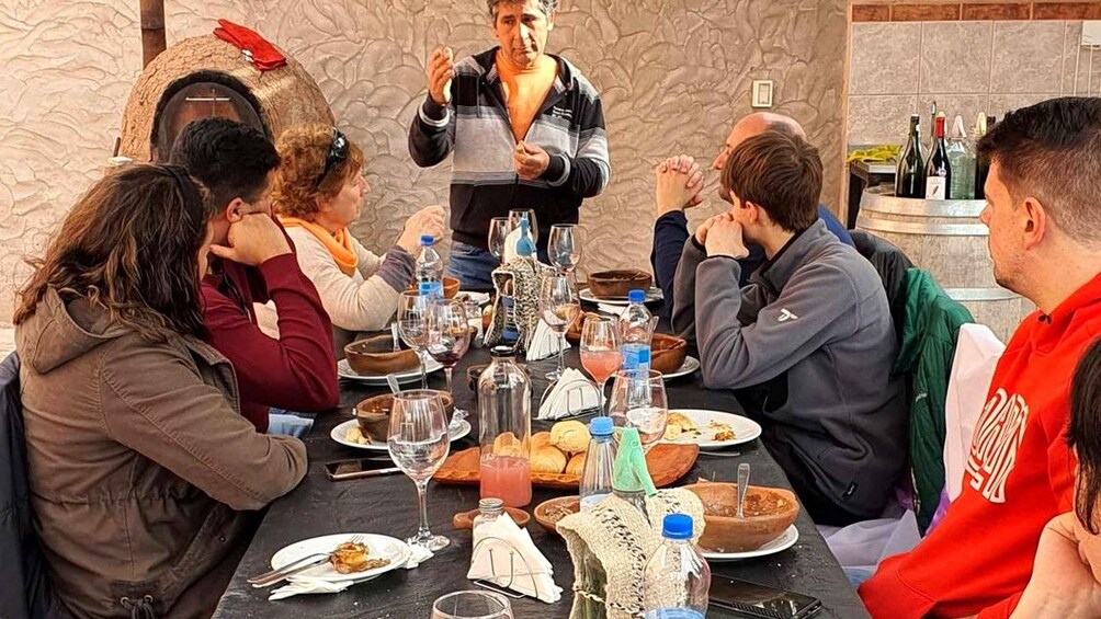 A group of people dining at a table with various dishes, glasses, and bottles. 2