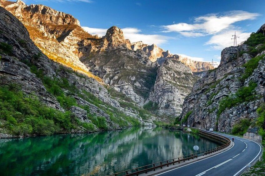 A winding road through a mountainous landscape with a lake reflecting the scenery. 5