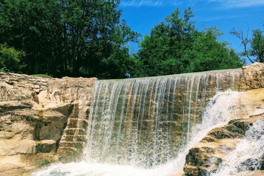 A waterfall cascading over rocky terrain with dense green foliage in the background. 4