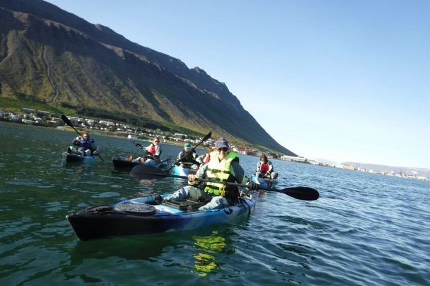 People kayaking on a calm lake with mountains in the background. 5