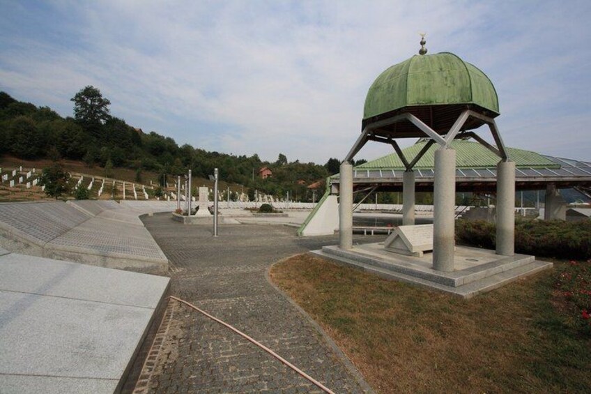A green-roofed pavilion, a paved walkway, and a cemetery with headstones. 4