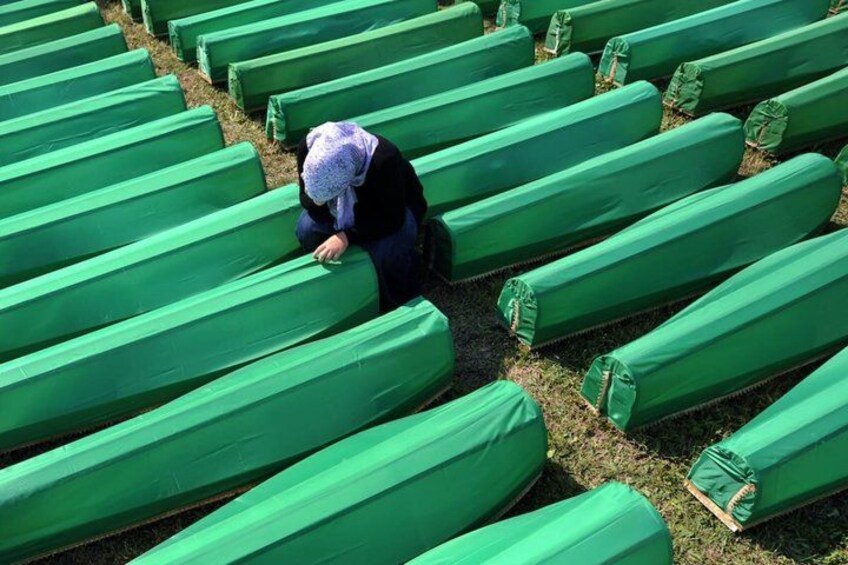 A person sitting on a green bench in a row of green benches. 3