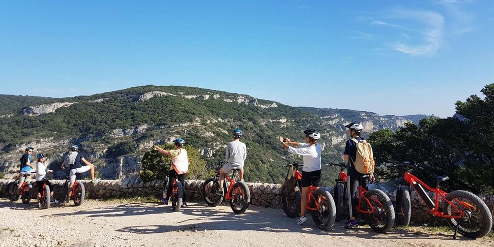 A group of people on mountain bikes on a dirt path with a scenic view of a mountainous landscape. 2