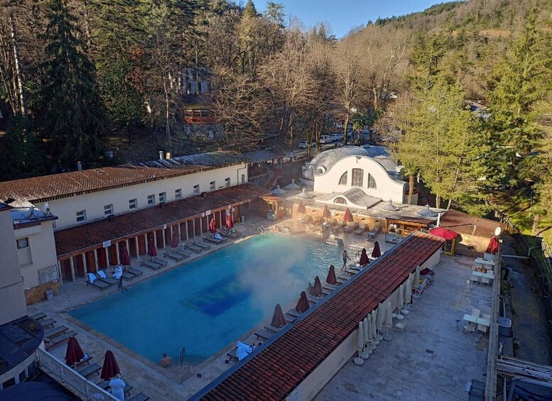 A swimming pool surrounded by lounge chairs and umbrellas, with a building in the background. 2