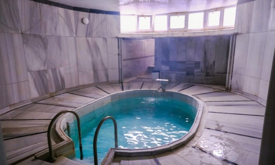 A swimming pool with a curved design, surrounded by marble walls and a tiled floor. 3