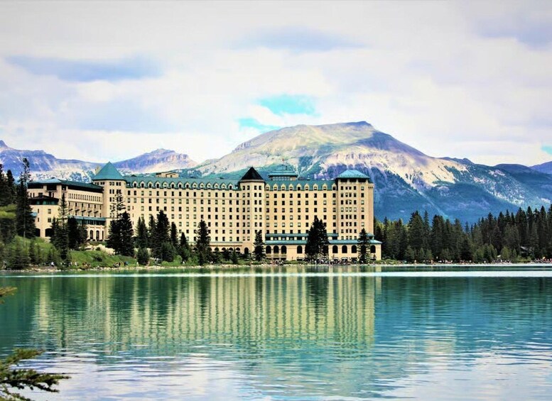 Un grand hôtel situé au pied d’une montagne, avec un lac paisible en contrebas. 1