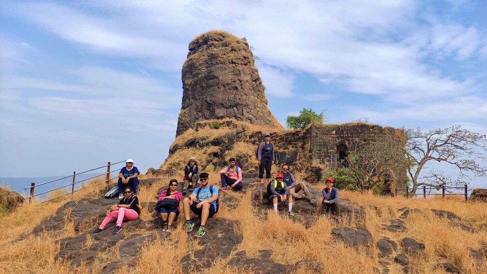 Eine Gruppe von Menschen sitzt auf Felsen, im Hintergrund eine große Felsformation. 5