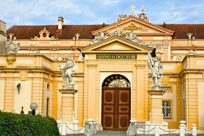 A historic building with ornate architecture, a large arched entrance, and statues. 1
