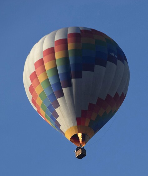Un ballon à air chaud aux couleurs de l’arc-en-ciel s’élève dans un ciel bleu dégagé. 3