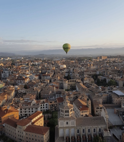 Une montgolfière survolant une ville dense, caractérisée par une architecture historique. 2