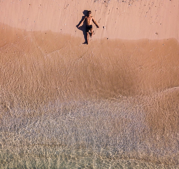 A person running on a sandy beach with clear shallow water. 2