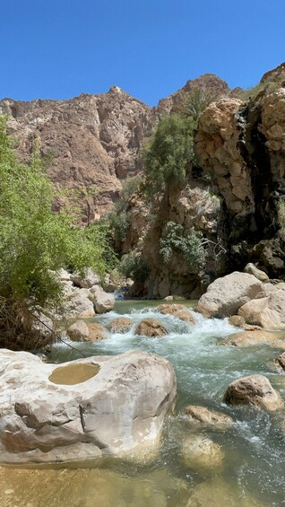 Une rivière qui serpente à travers un canyon rocheux, avec des eaux claires, bordée de gros rochers et d’une végétation clairsemée. 3