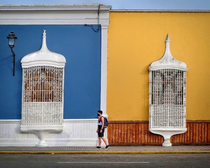 A street with a blue building and a yellow building, each with a white decorative structure. 2