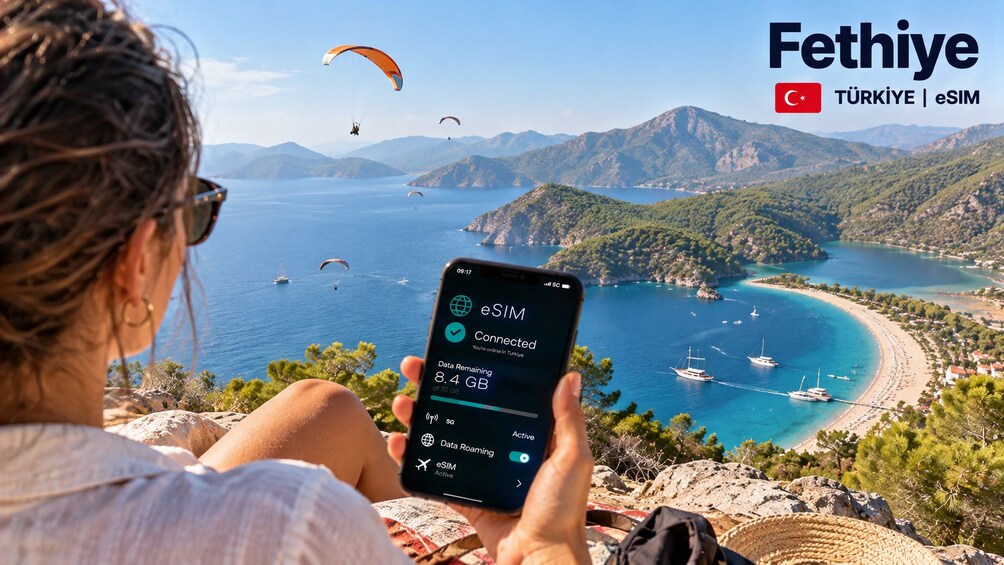 A person using a smartphone with a scenic coastal view in the background. 5